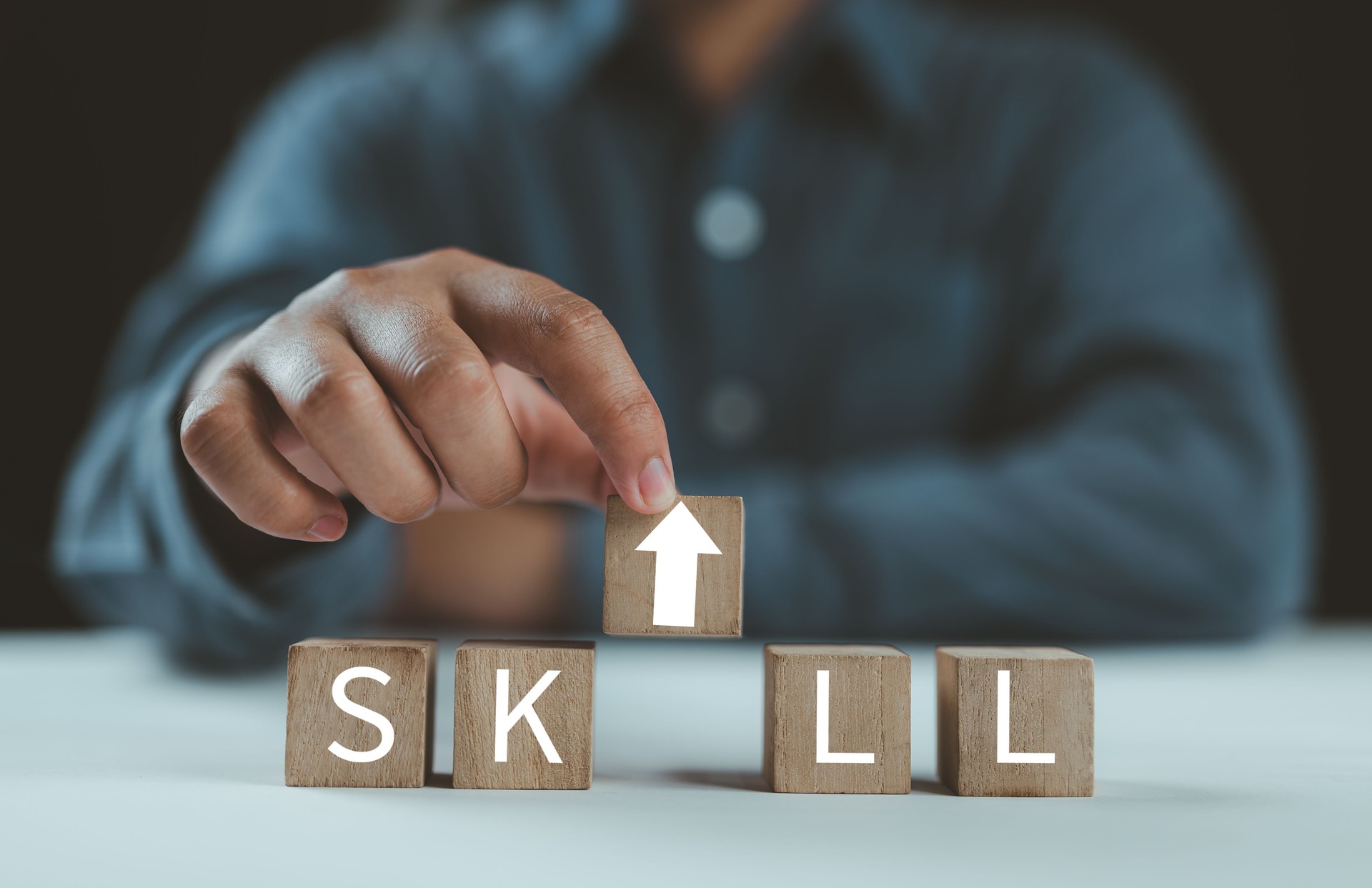 Hand select the arrow up icon with SKILL words on wooden cubes. Upskilling and personal development concept. Upskill training, knowledge and education, learning, ability. Up-skilling, Re-skilling.
